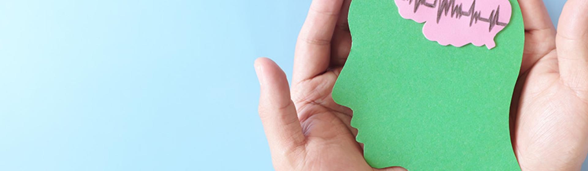 Hands holding green head representing mental health